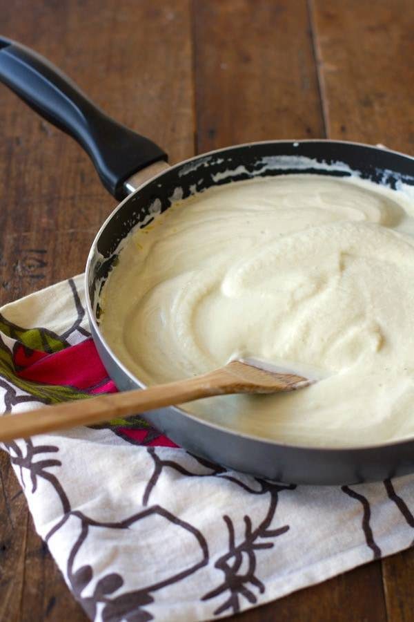 Creamy cauliflower sauce in a skillet with a wooden spoon.