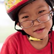 A young boy with glasses and a bike helmet on.