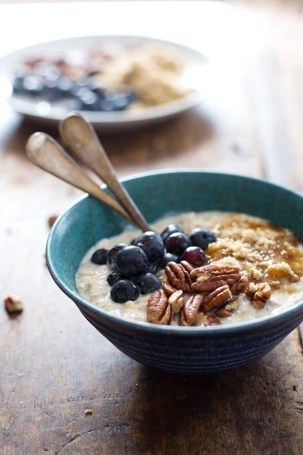 Overnight oats with flax, blueberry, and vanilla yogurt in a blue bowl with spoons.