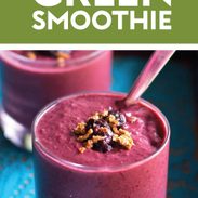 Berry green smoothie in a glass with granola on top.
