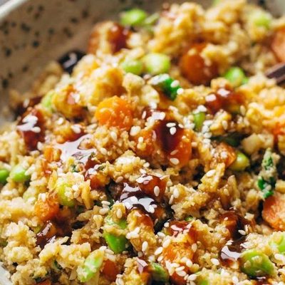 Cauliflower fried rice in a bowl with chopsticks.