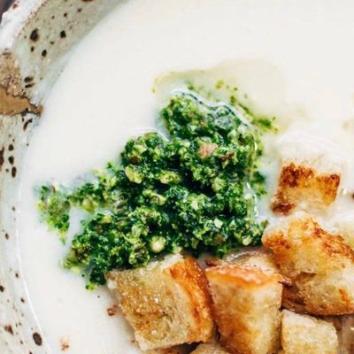 Cheesy Cauliflower Soup in a bowl with pesto and croutons.
