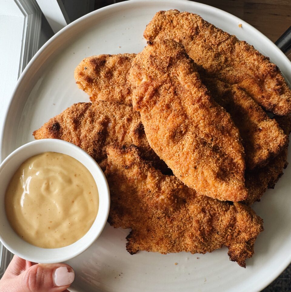 Air fryer chicken tenders on a plate with honey mustard sauce.