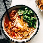 Chicken Tortilla Soup in a bowl with toppings and a spoon.