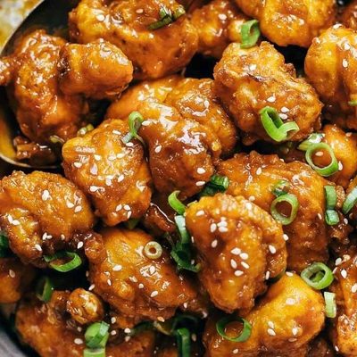 General Tso's Cauliflower in a pan with a spoon.
