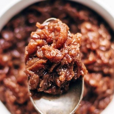 Caramelized Shallot and Grape Chutney in a jar with spoon.