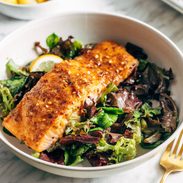 A piece of salmon sitting on a bed of greens.