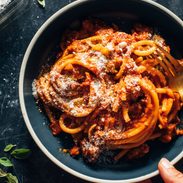 Bucatini in a bowl with red sauce and pecorino on top.