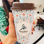 White woman holding holiday themed coffee cup.