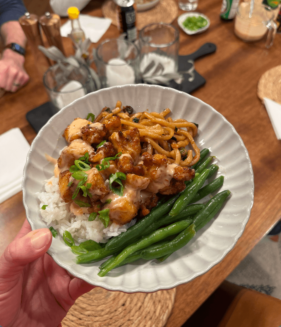 Bang bang tofu on a plate with green beans and noodles.