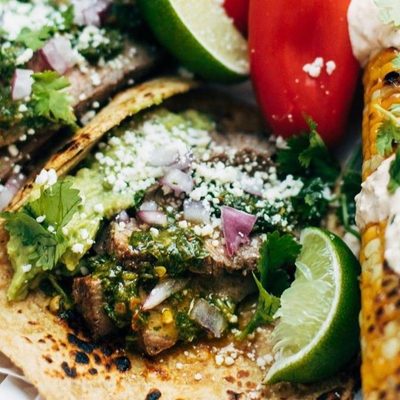 Steak Tacos on plates with hand squeezing a lime.