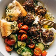 Meatballs in a bowl with a tomato salad and bread