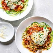 Chicken parmesan on a plate of zucchini noodles.